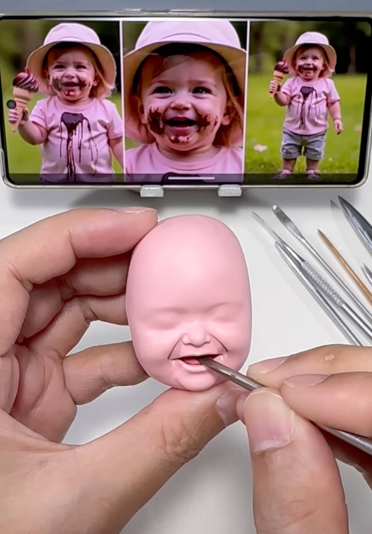 Carving the eyes, nose and smile into the clay head