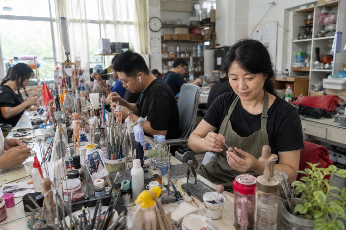 An artist holding a clay head the size of a grape